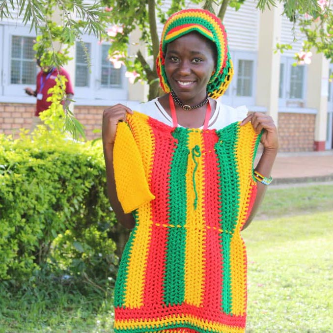 woman holding crocheted hat and shirt